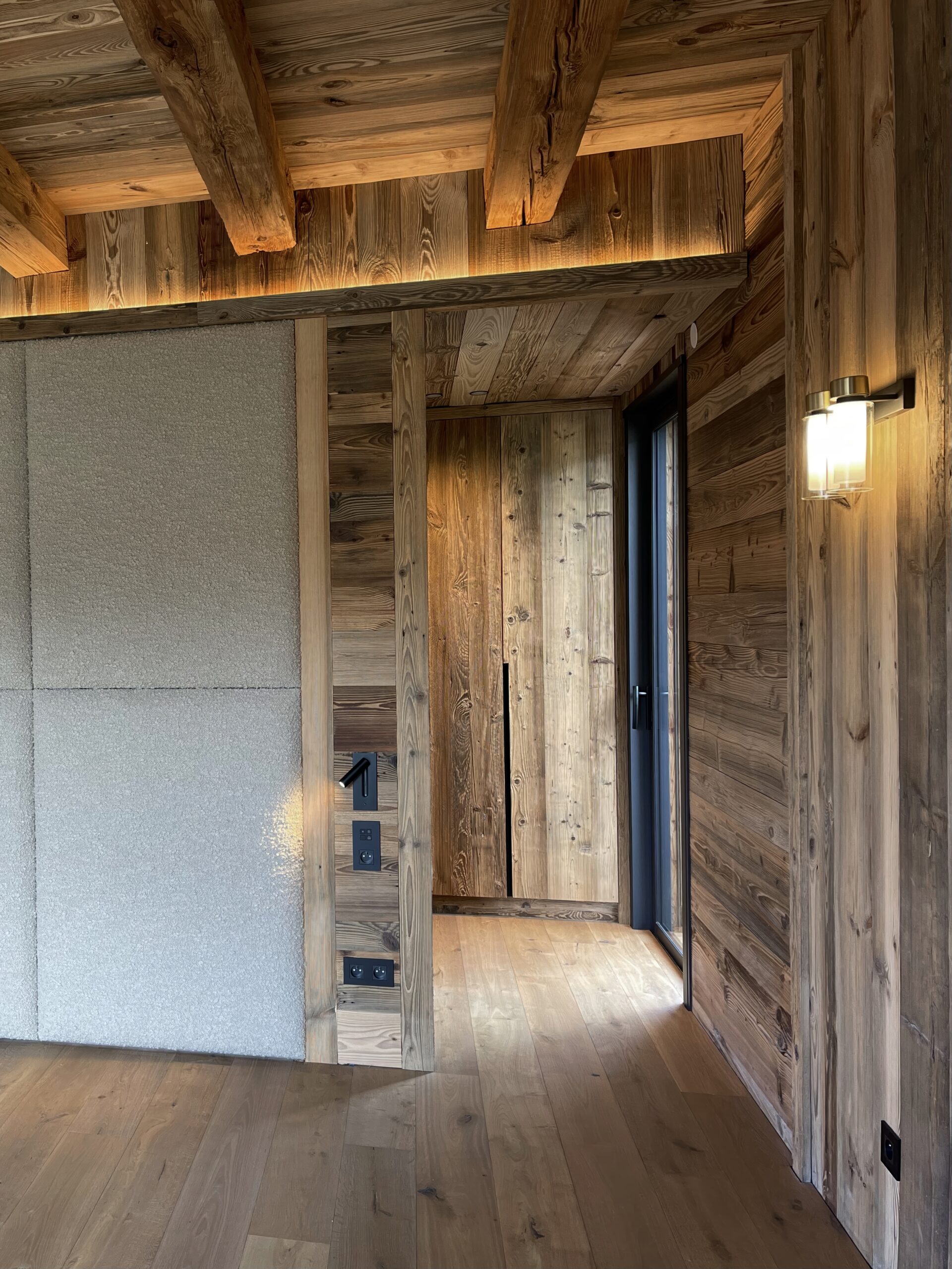 Architecte d'intérieur luxe à Megève avec aménagements sur mesure en bois vieilli, tête de lit en tissus et dressing portes en bois