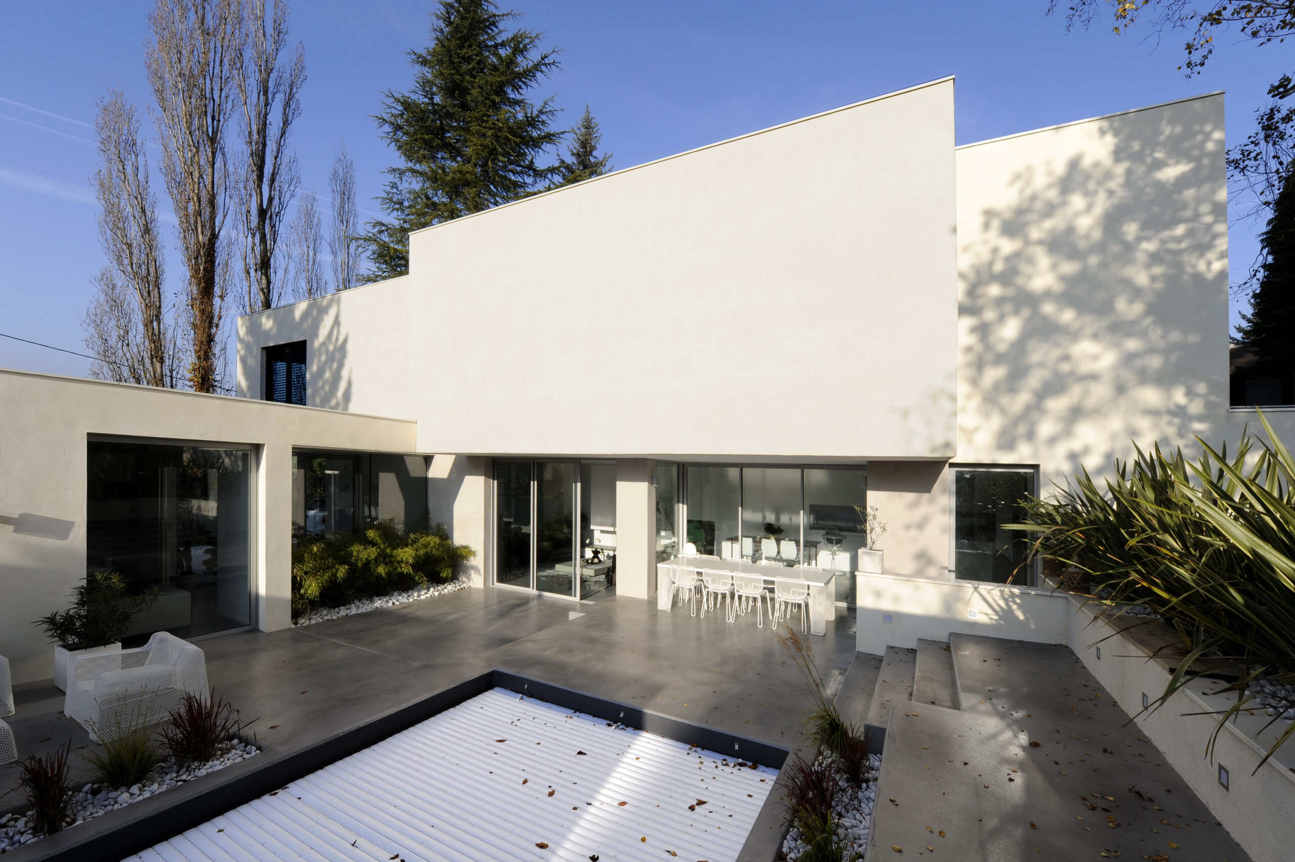 Villa d'architecte luxe Lyon avec piscine à couverture automatique, terrasse en béton ciré grandes baies vitrées