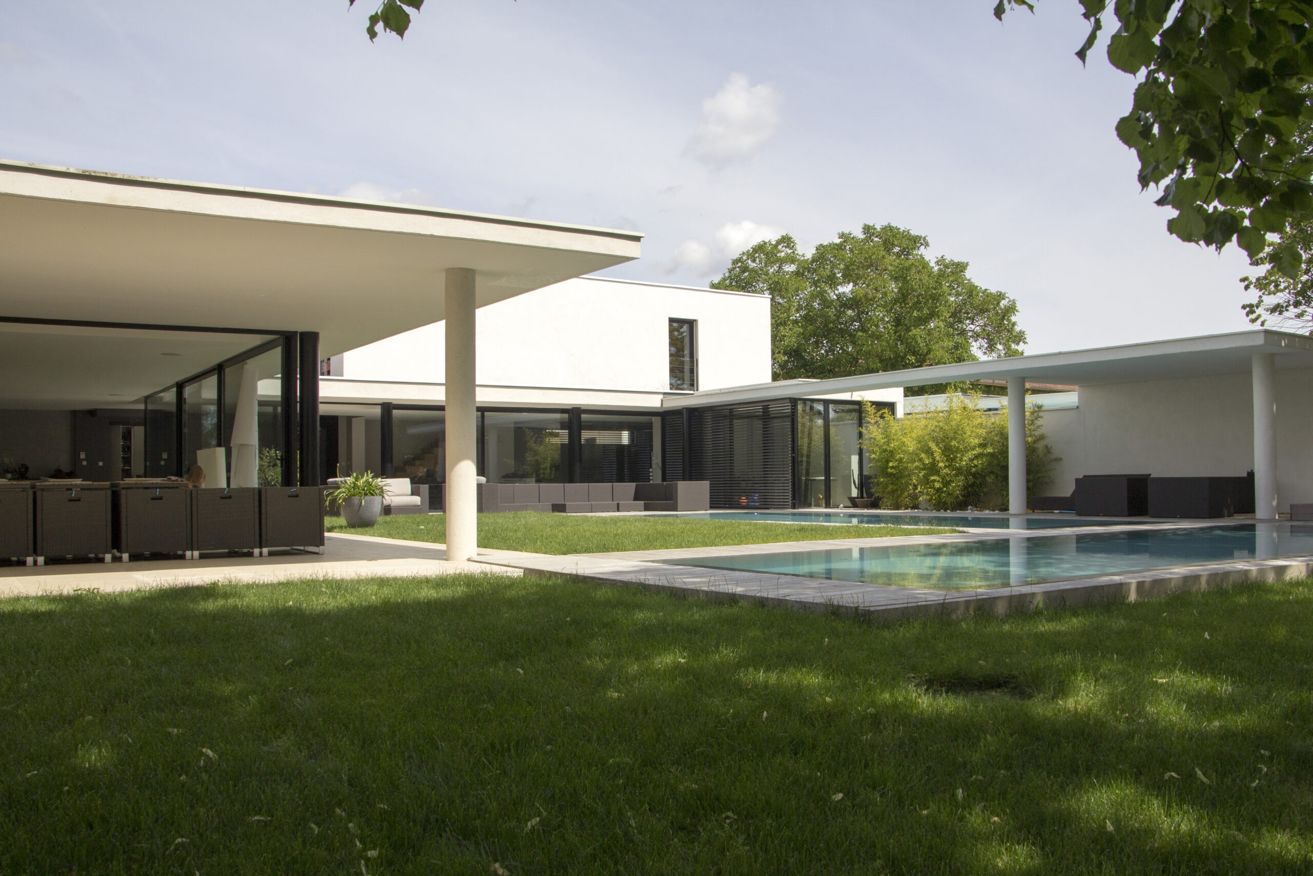 Villa contemporaine à Dommartin avec double piscine miroir et baies vitrées toute hauteur en aluminium noir, et brises-soleil orientables